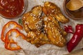 Fried juicy chicken wings marinated with honey, soy sauce, spices, sprinkled with sesame seeds on paper on a wooden background. Royalty Free Stock Photo