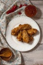 Fried juicy chicken wings marinated with honey, soy sauce, spices, sprinkled with sesame seeds on a white plate with sauce. Asian Royalty Free Stock Photo