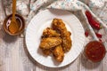 Fried juicy chicken wings marinated with honey, soy sauce, spices, sprinkled with sesame seeds on a white plate with sauce. Asian Royalty Free Stock Photo