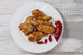 Fried juicy chicken wings marinated with honey, soy sauce, spices, sprinkled with sesame seeds on a white plate on a Royalty Free Stock Photo