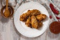 Fried juicy chicken wings marinated with honey, soy sauce, spices, sprinkled with sesame seeds on a white plate with sauce. Asian Royalty Free Stock Photo