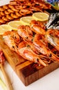 Fried langoustines and fried mussels with sauce and fried shrimps and sliced lemon on wooden cutting board and jacinths Royalty Free Stock Photo