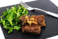 Fried liver, fresh arugula on black stone plate