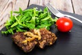 Fried liver, fresh arugula on black stone plate