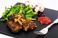 Fried liver, fresh arugula on black stone plate