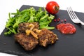 Fried liver, fresh arugula on black stone plate