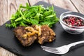 Fried liver, fresh arugula on black stone plate