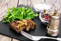 Fried liver, fresh arugula on black stone plate