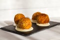 Fried meat balls or croquettes with white sauce on black stone plate on white wooden background. Unhealthy food Royalty Free Stock Photo