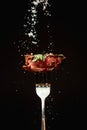 Fried meat on a fork is sprinkled with salt on a black background Royalty Free Stock Photo