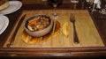 Fried meat and waxes on a dark frying pan on a wooden stand.