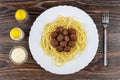 Fried meatballs with spaghetti in dish, salt, pepper, bowl with mayonnaise, fork on dark wooden table. Top view