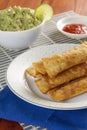Fried Mexican delicious taquitos on a plate accompanied with guacamole in a bowl and some ketchup