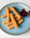 Fried Mozzarella Sticks with Marinara Sauce served on a light blue plate over white background. Isolated on white. Royalty Free Stock Photo