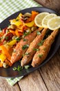 Fried mullet with stewed vegetables and lemon close-up on a plat