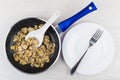 Fried mushrooms, plastic spoon in frying pan, empty plate, fork