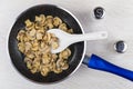 Fried mushrooms, plastic spoon in frying pan, salt and pepper