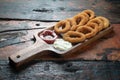 Fried onion rings with ketchup and mayonnaise on rustic wooden table Royalty Free Stock Photo