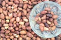 Fried peanuts in small glass bowl and lot of roasted peanut fruits as background top view Royalty Free Stock Photo