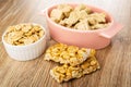 Peanuts in bowl, pieces of peanut halva in oval bowl, pieces of kozinak on wooden table