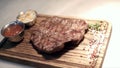 Fried piece of meat served on wooden tray. Action. Close-up of juicy piece of steak cooked by professional chef and Royalty Free Stock Photo