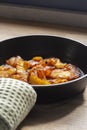 Fried pineapple in a cast iron frying pan. On a wooden chopping board