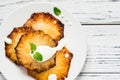 Fried pineapple slices with creme fraiche, white table. Top view