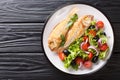 Fried pink dorado served with lemon and fresh vegetables close-up on a plate. Horizontal top view