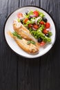 Fried pink dorado served with lemon and fresh vegetables close-up on a plate. Vertical top view