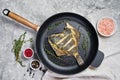 Fried plaice in a pan. Gray background, top view. Royalty Free Stock Photo