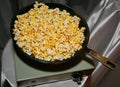 Fried popcorn in an old cast iron skillet on the light green vintage electric tile on the background of gray-silver fabric draping Royalty Free Stock Photo