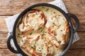 Fried pork chops on the bone served in a creamy cheese sauce with herbs close-up in a pan. Horizontal top view Royalty Free Stock Photo