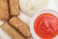 Fried Pork Lumpiang Shanghai, a Filipino egg roll, served with sweet and sour sauce and a cup of rice. Philippine cuisine