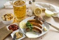 Fried pork sausages with greens , onions, spices on a plate, sausages with ketchup, mustard, sausage on a fork, garlic , a mug of Royalty Free Stock Photo
