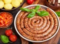 Fried pork sausages served with boiled potatoes, sauce, tomatoes and basil leaf Royalty Free Stock Photo