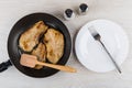 Fried pork schnitzel in frying pan, salt, pepper, plate, fork