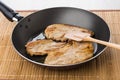 Fried pork schnitzel in frying pan and spatula on mat