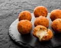 Fried potato cheese balls or croquettes with spices on black plate over dark stone background. Unhealthy food, top view