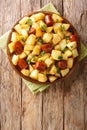 Fried potato wedges with sausages and herbs close-up in a plate. Vertical top view Royalty Free Stock Photo