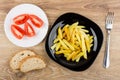 Fried potatoes in black plate, tomatoes, bread and fork Royalty Free Stock Photo
