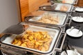 Fried potatoes garnish and meat on skewers in a food warmer on a buffet table in a hotel restaurant Royalty Free Stock Photo