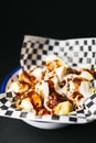 Fried potatoes with mayonnaise and spacy sauce over a black background