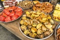 Fried potatoes sliced in large slices laid on a large metal plate, with fried sausage and baked vegetables on the fast food table Royalty Free Stock Photo