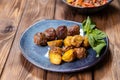 Fried potatoes in a uniform and meat cutlets in a plate with greens