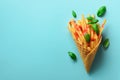 Fried potatoes in waffle cones on blue background. Hot salty french fries with tomato sauce, basil leaves. Fast food