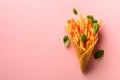 Fried potatoes in waffle cones on pink background. Hot salty french fries with sauce, basil leaves. Fast food, junk food Royalty Free Stock Photo