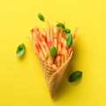 Fried potatoes in waffle cones on yellow background. Hot salty french fries with sauce, basil leaves. Fast food, junk Royalty Free Stock Photo