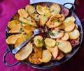 Fried potatoes in wedges with eggplant and pomegranate seeds in large frying pan Royalty Free Stock Photo