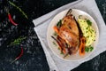 Fried rabbit leg, garnish of boiled potatoes, grilled carrots - on a plate on a dark background. Royalty Free Stock Photo