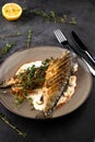 Fried rainbow trout fish with lemon sauce and thyme on black marble table as background Royalty Free Stock Photo